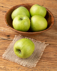 Green apples in a bowl over wooden table