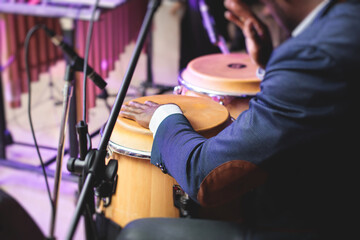 Bongo drummer percussionist performing on a stage with conga drums set kit during jazz rock show...