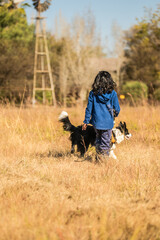 Kid walking a dog on a leash in a field with brown