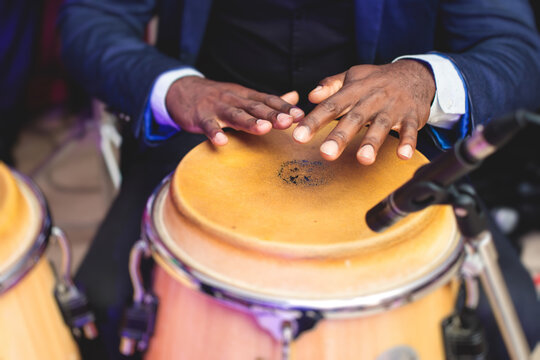 Bongo Drummer Percussionist Performing On A Stage With Conga Drums Set Kit During Jazz Rock Show Performance, With Latin Cuban Band Performing In The Background, Drummer Point Of View