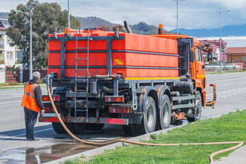 Driver fills with water cleaning machine on the city street.
