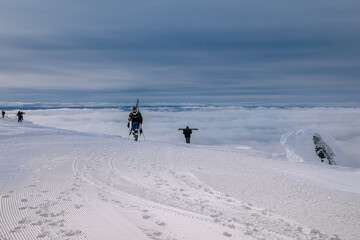 Freeriders skiers and snowboarders on a mountain slope against a background of fog in ski resort in...