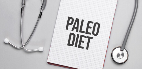 On a beige background, a stethoscope and a white notepad with the inscription paleo diet. Medical concept