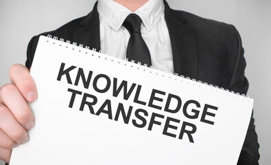 Businessman holding a card with text KNOWLEDGE TRANSFER