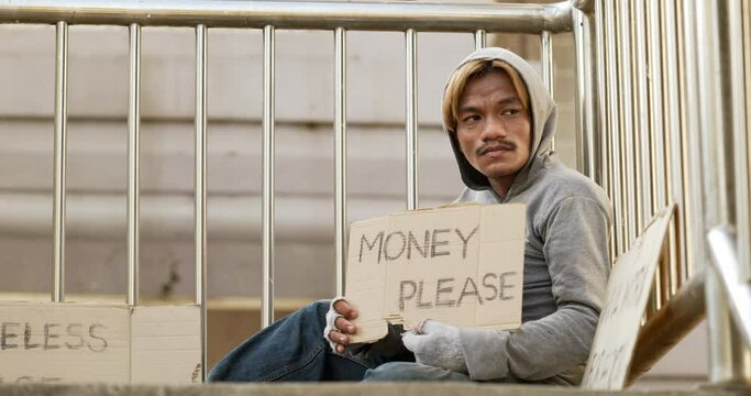 Homeless man sitting and holding money please sign on the overpass