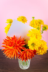 Blank greeting card in bouquet of yellow summer flowers on pink background. Holiday invitation, place for text.