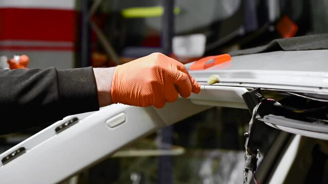 Close up of Automobile technician worker replacing windscreen of a car in automobile service station garage. High quality 4k footage