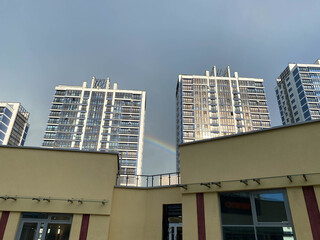 Beautiful tall new buildings on the background of blue sky and rainbow in a big city