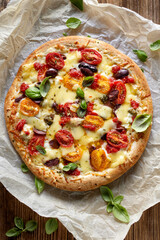Vegetarian pizza with cherry tomatoes, kalamata olives and fresh basil, top view