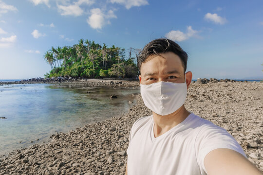 Asian man with face mask has a summer sea trip while in Covid-19 pandemic.