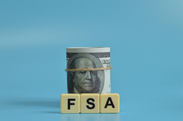 Money banknotes and alphabet letters with text FSA stands for Flexible Spending Account.