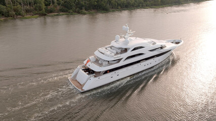 Large mega yacht underway along the coast, low aerial view.