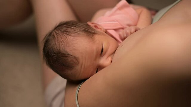 The camera zooms in and shows a close-up of a newborn baby being milked by a young mother