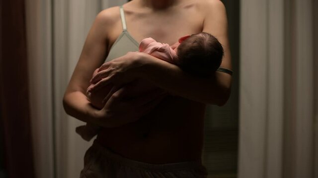 The camera zooms out from the newborn baby, which the mother is breastfeeding, holding in her arms