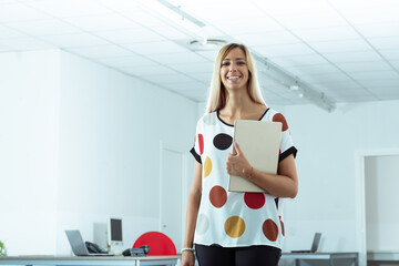 Happy friendly businesswoman in a modern open plan office