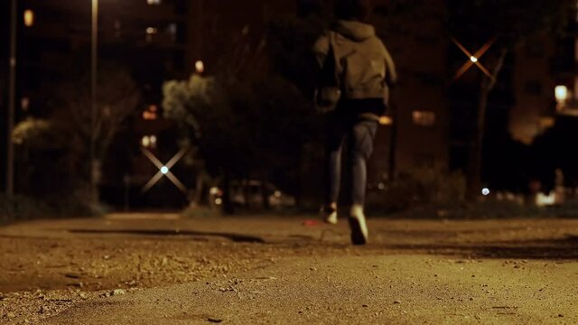 danger, fear - young man in the city at night runs to escape from his attacker