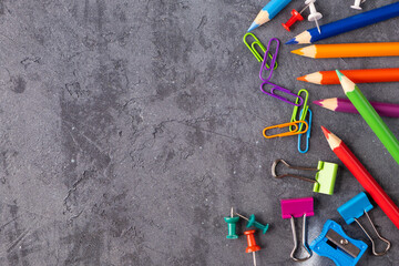 Top view of pencils color, paper clips and push pins on concrete texture background