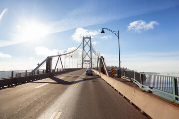 Fototapeta premium Drive across the famous Lions Gate Bridge in the modern Downtown City. Sunny Winter Day. Vancouver, British Columbia, Canada