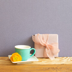 Gift box and mint green coffee cup on wooden table. purple background