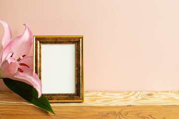 Empty picture frame with lily flower on wooden table. pink background