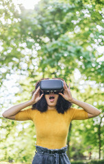 Afro woman wearing a virtual reality glasses in a garden.