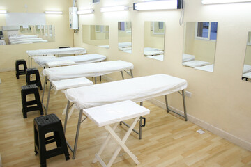 Group of massage tables in light and bright cabinet with mirrors on the wall.