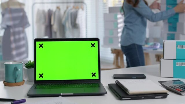 Notebook green screen on desk table home office designer studio workplace e-commerce startup sme with asia female worker work background supply chain logistic delivery template wifi network concept.