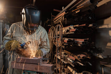 A welder is welding steel in an industrial factory. The welder wears protective clothing to work in the workplace.