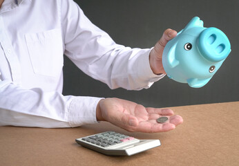 Businessman emptying piggybank savings. Only one coin left. Broke or financial crisis concept.