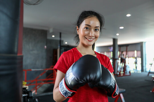 Beautiful Women Asian Boxer Happy And Fun Fitness Boxing And Punching A Bag With Wearing Boxing Gloves.