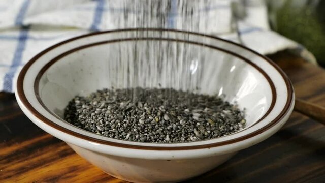 Pouring black chia seeds into a bowl in super slow motion