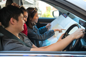 Happy Asian friends with map in car on road trip