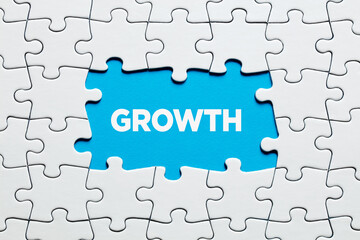 Fototapeta premium The word growth on blue background surrounded by jigsaw puzzle. Business, financial or personal growth concept.