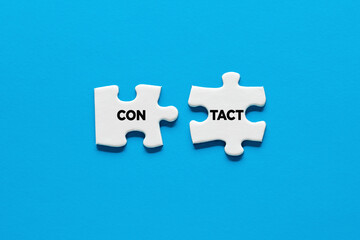 Two puzzle pieces with the word contact. Communication, cooperation and interaction