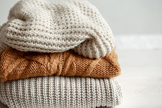 A stack of warm knitted sweathers on blurred background.