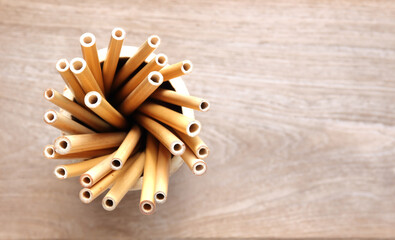 bamboo straw in bamboo cylinder on wood background with copy space ( straw from natural material / green product concept )