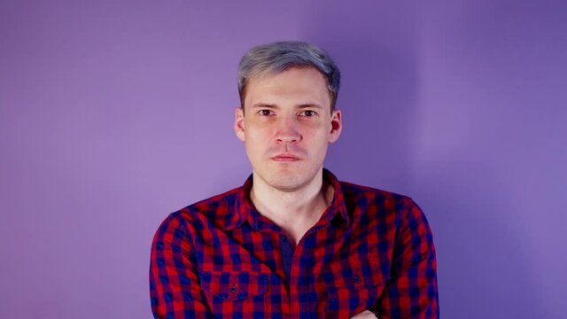 Close up of young man getting slapped in face on purple background. Unrecognizable woman hits cheeky guy on cheek deservedly.