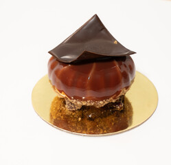 Brown glaze pastry on gold plate with chocolate square on top
