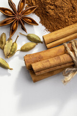 A slide of ground cinnamon, cinnamon rolls, cardamom, anise on a white background, studio shot, copy space.