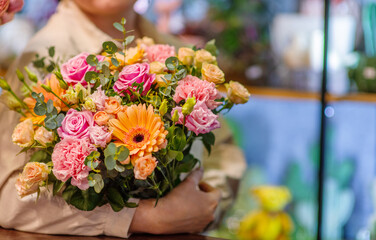 Florist at work: woman making fashion modern bouquet of different flowers on wooden background. Masterclass. Gift for bride on wedding, mother
