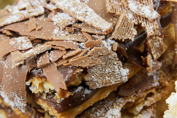 Puff pastry cakes with powdered sugar and cream and another with chocolate and a cherry on top on the wooden table. Macro close up. Selective focus.
