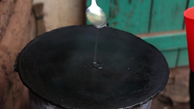 Pouring cooking oil on the flying pan when getting ready to make the African Street ,