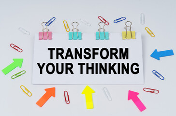 On the table there are paper clips and directional arrows, a sign that says - Transform Your Thinking