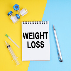 A syringe, ampoules and a notebook with the inscription - weight loss
