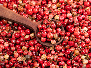 spoon on pile of pink peppercorns closeup