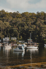 Fototapeta na wymiar Boats on the water in front of idyllic waterfront houses at Berowra Waters NSW. As seen from the Great North Walk.