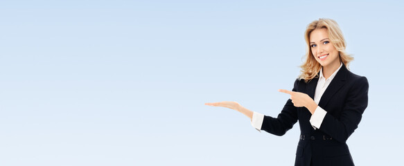 Portrait of happy smiling young cheerful businesswoman, showing something or blank copyspace area...