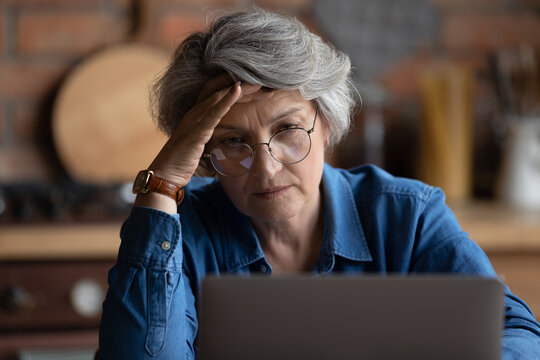 Mature woman looks at laptop screen feels confused has difficulties with device, not understand, need help in learn, wrong password, older gen and problems with modern tech, lack of technology skills