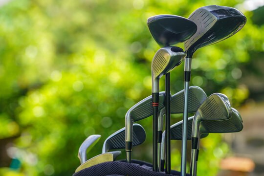 Golf bag and clubs in front of a blurred golf course background,
