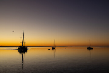 Fototapeta na wymiar sunset with sail boats in mirror like ocean at Monkey Mia, Western Australia